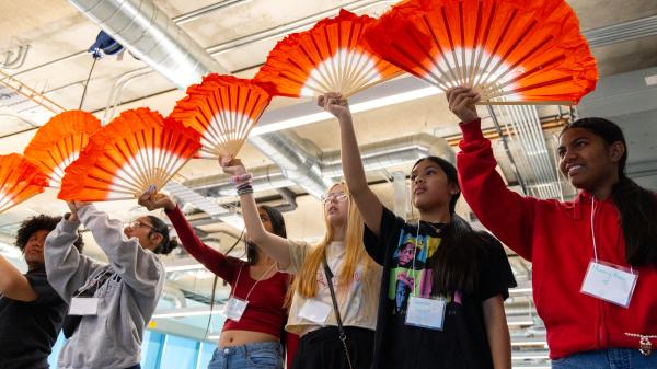 High school students smiling with orange fans in their hands